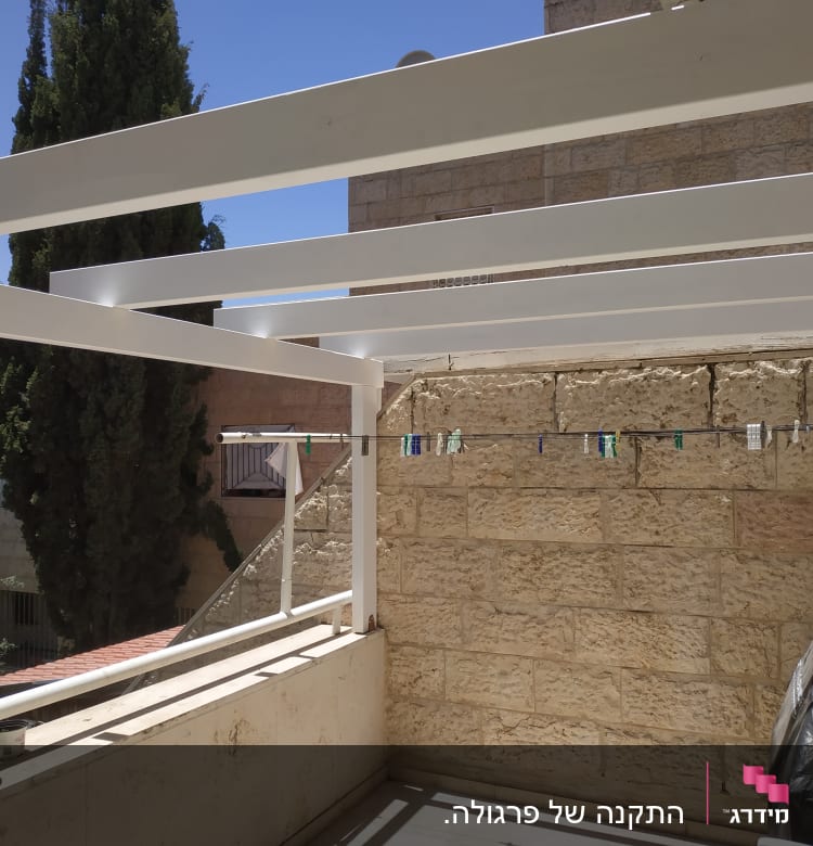 מרפסת עם קורות עץ לבנות וחבל כביסה
